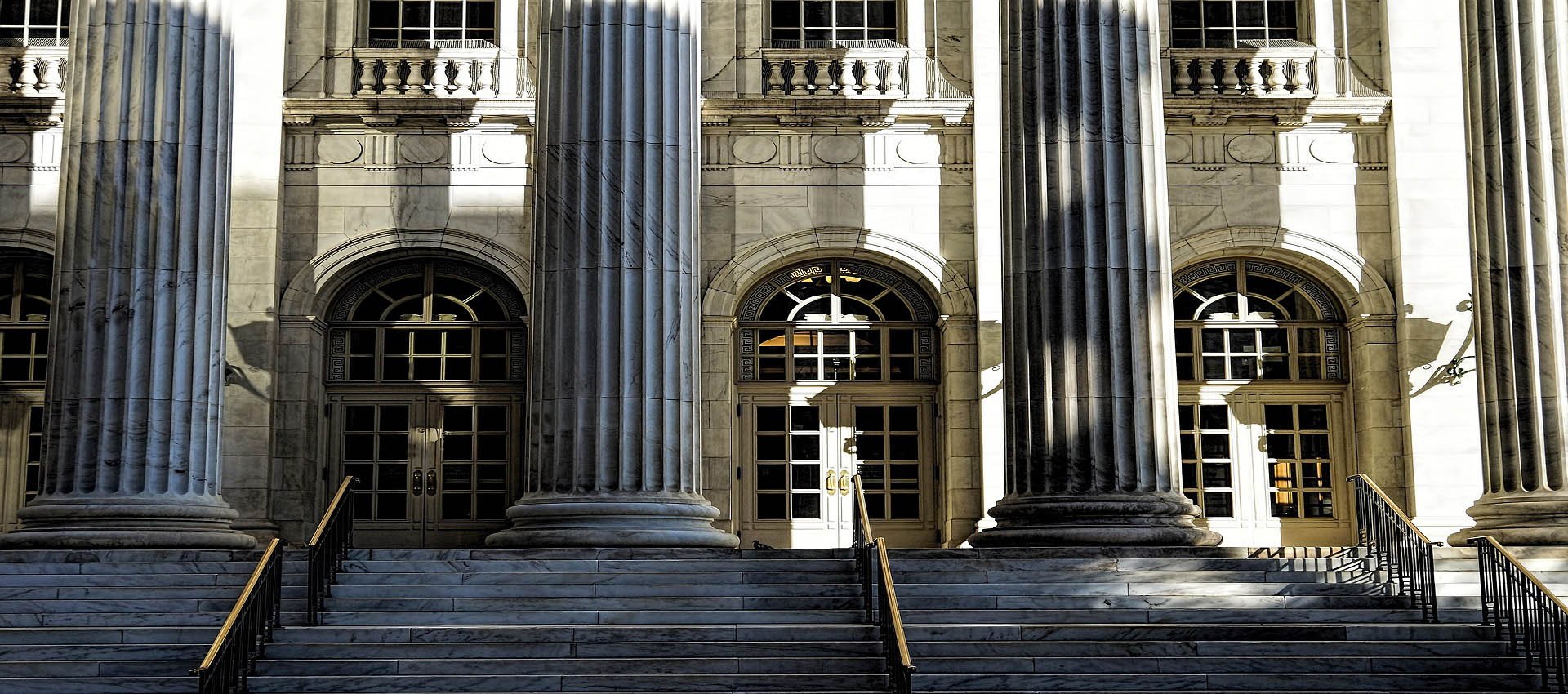 This image features the entrance to a courthouse. The photo includes steps leading to a grand entrance with enormous pillars.